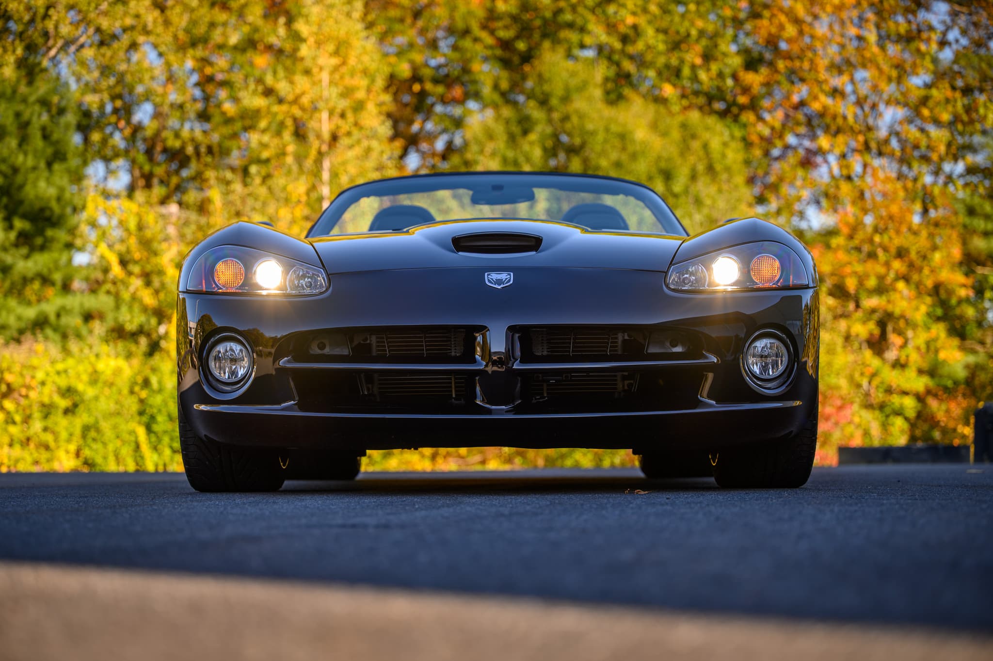 Dodge Viper with headlights on in New England fall foliage — automotive photography